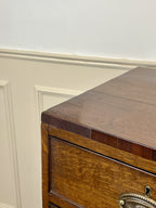 Wooden dresser with a metal handle against a white wall.