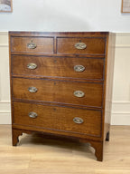Wooden dresser with four drawers and metal handles on a wooden floor.