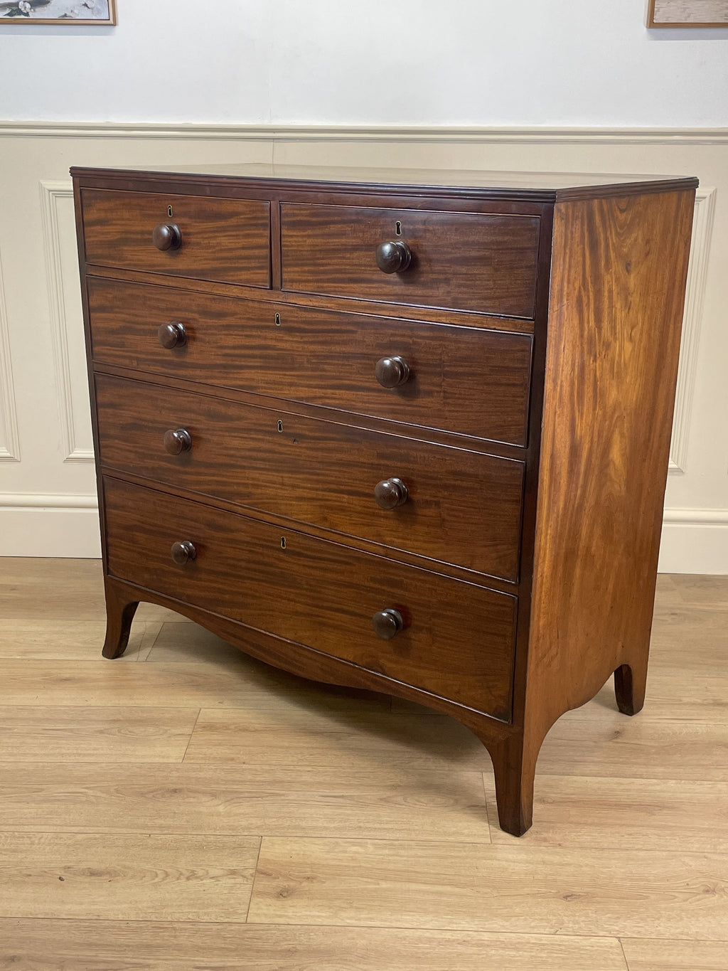 Wooden dresser with multiple drawers on a wooden floor.