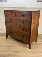 Wooden dresser with multiple drawers on a wooden floor.