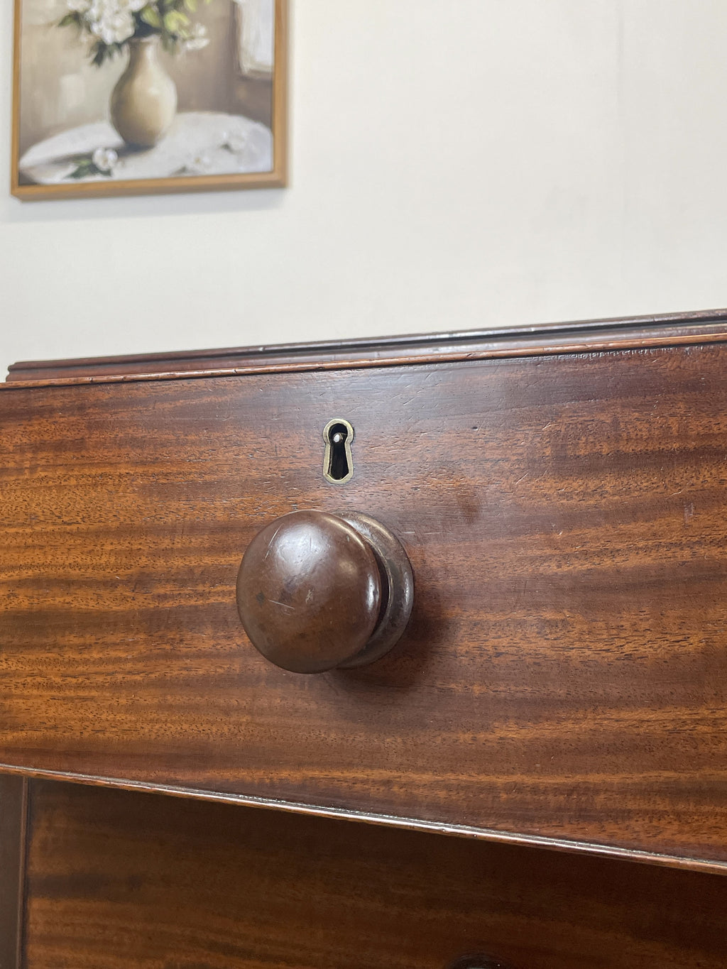 Close-up of a wooden drawer with a knob and lock, with a blurred background.
