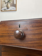 Close-up of a wooden drawer with a knob and lock, with a blurred background.