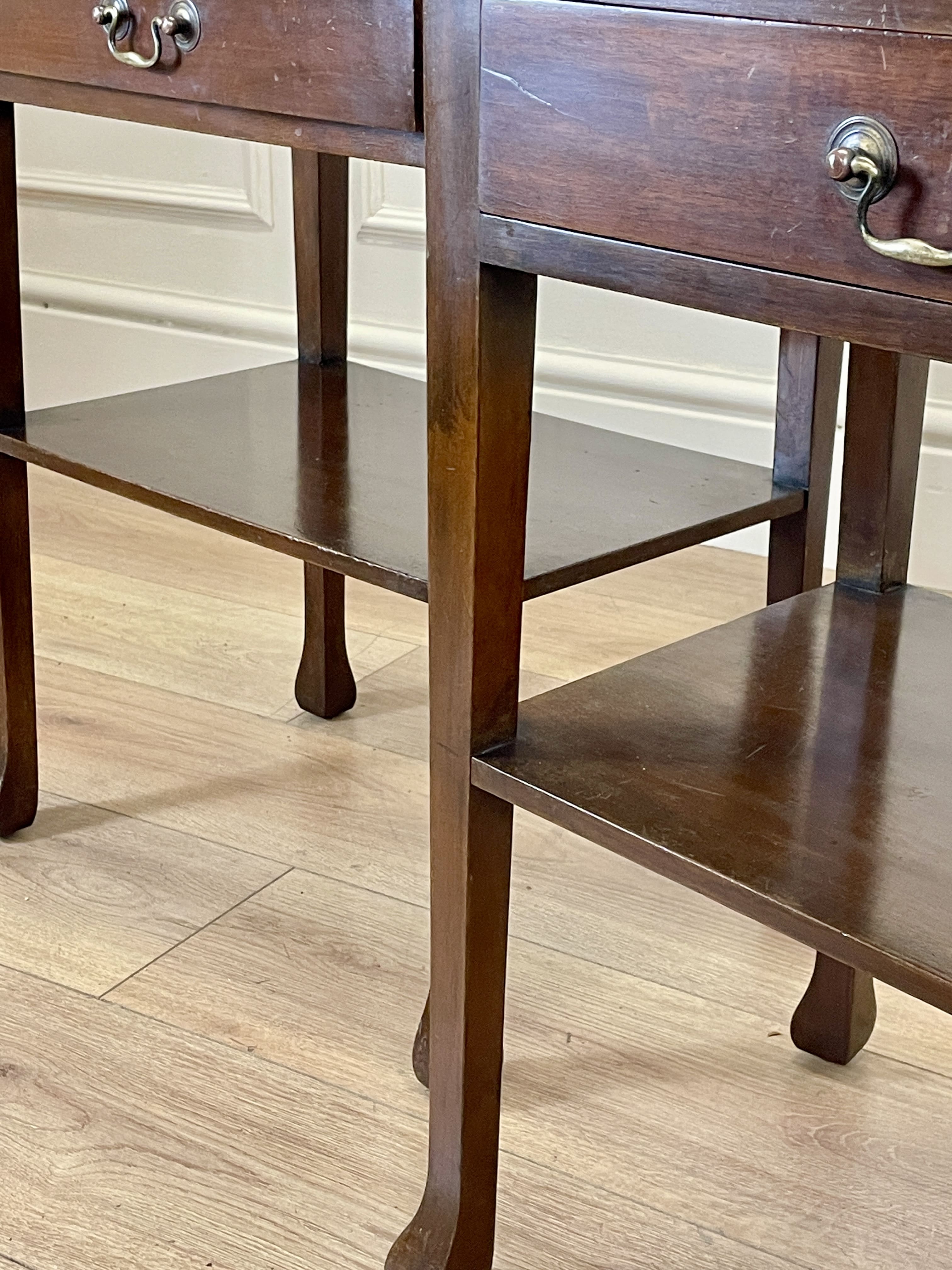 Wooden side table with two drawers on a wooden floor.