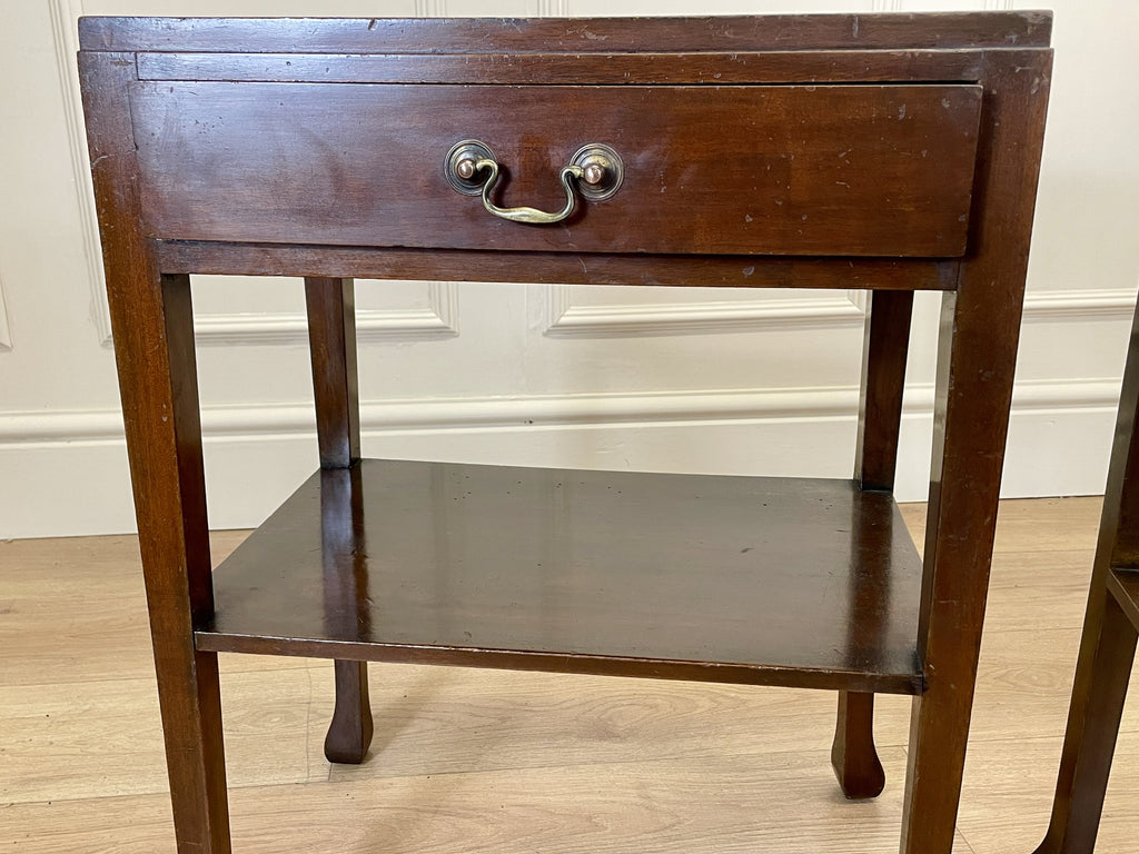 Wooden side table with a drawer and shelf against a white wall.