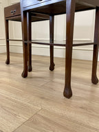Wooden side table with a drawer on a wooden floor.