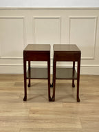 Two wooden side tables against a paneled wall.