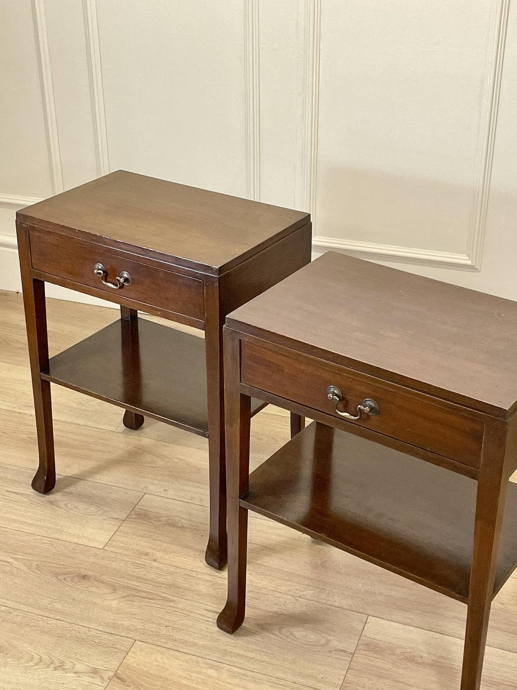 Two wooden side tables with drawers on a wooden floor.