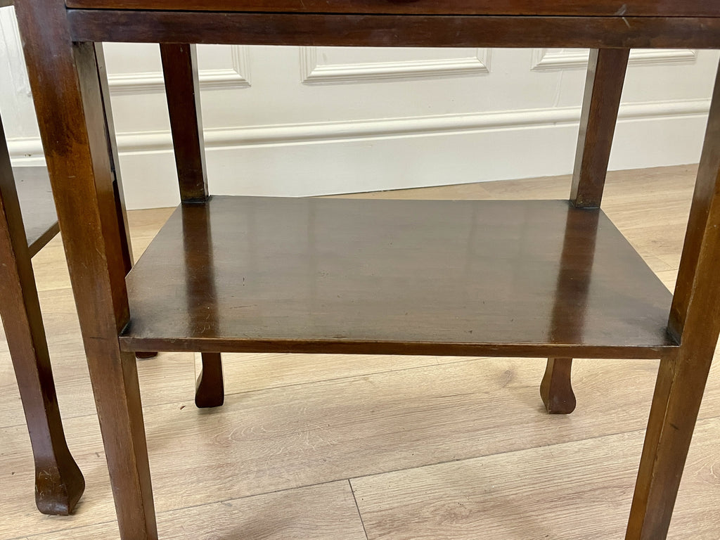 Wooden side table with a single shelf on a wooden floor.