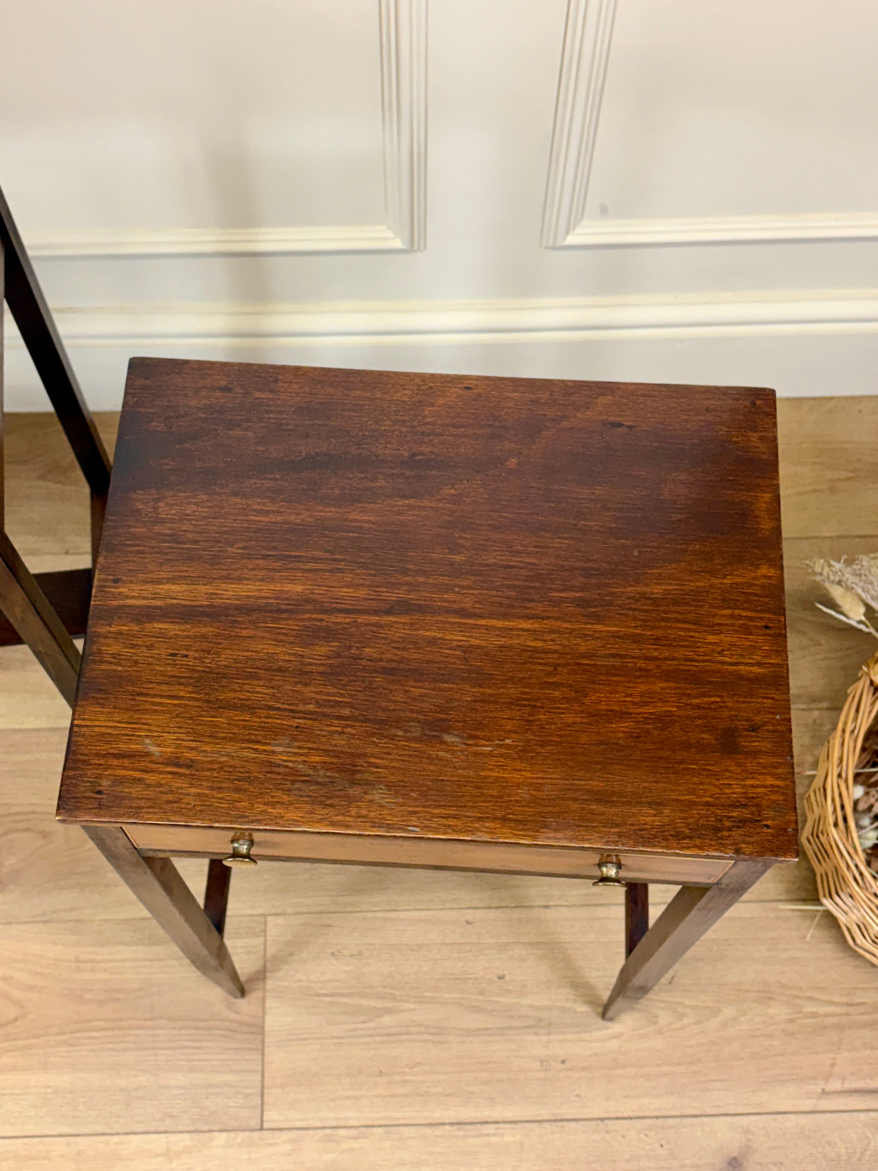 Wooden side table with a wicker basket on a wooden floor.