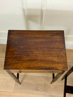 Wooden side table with a drawer on a wooden floor.
