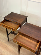 Two wooden side tables with drawers on a wooden floor.