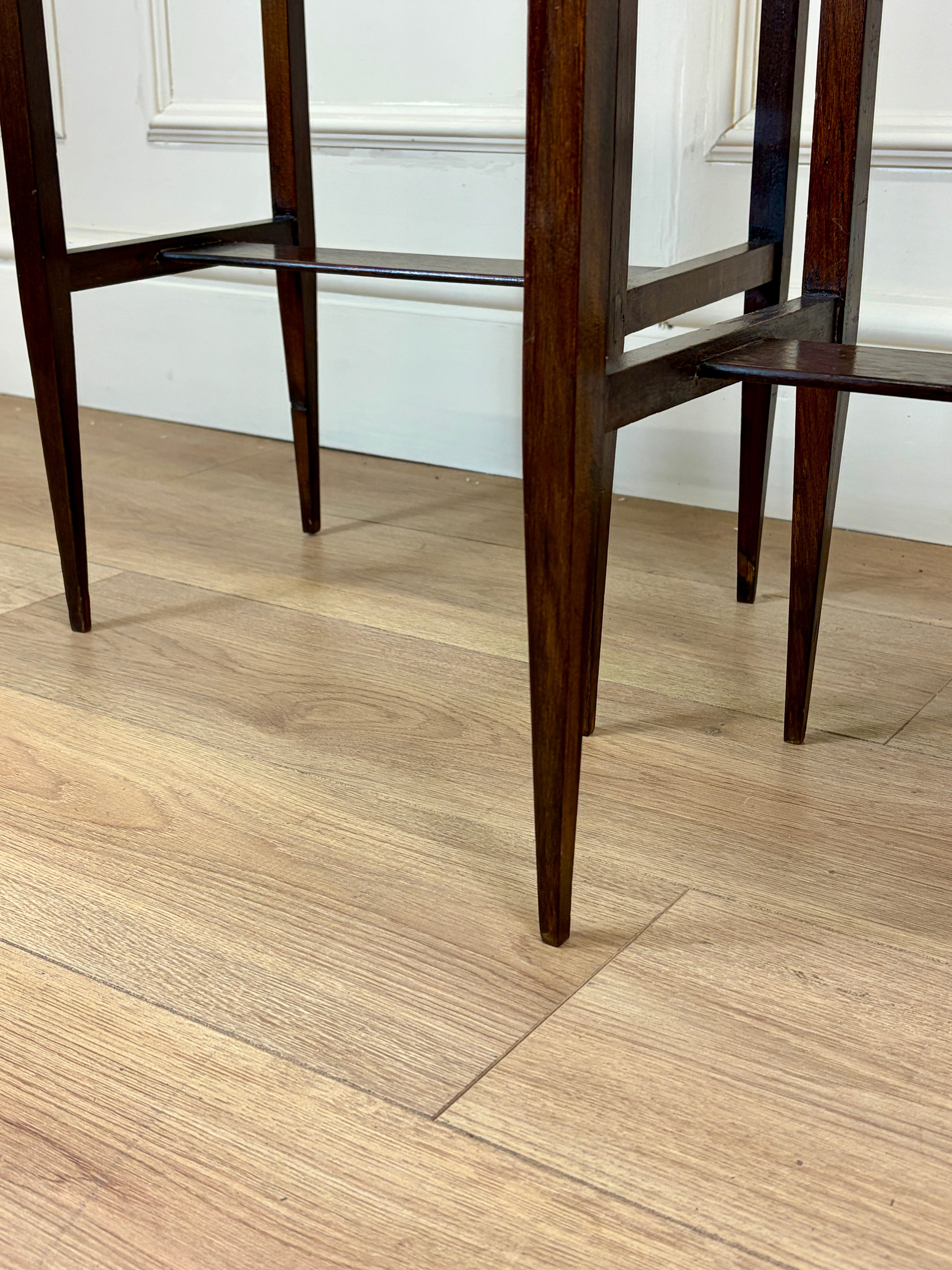 Wooden chairs on a wooden floor with a white wall in the background