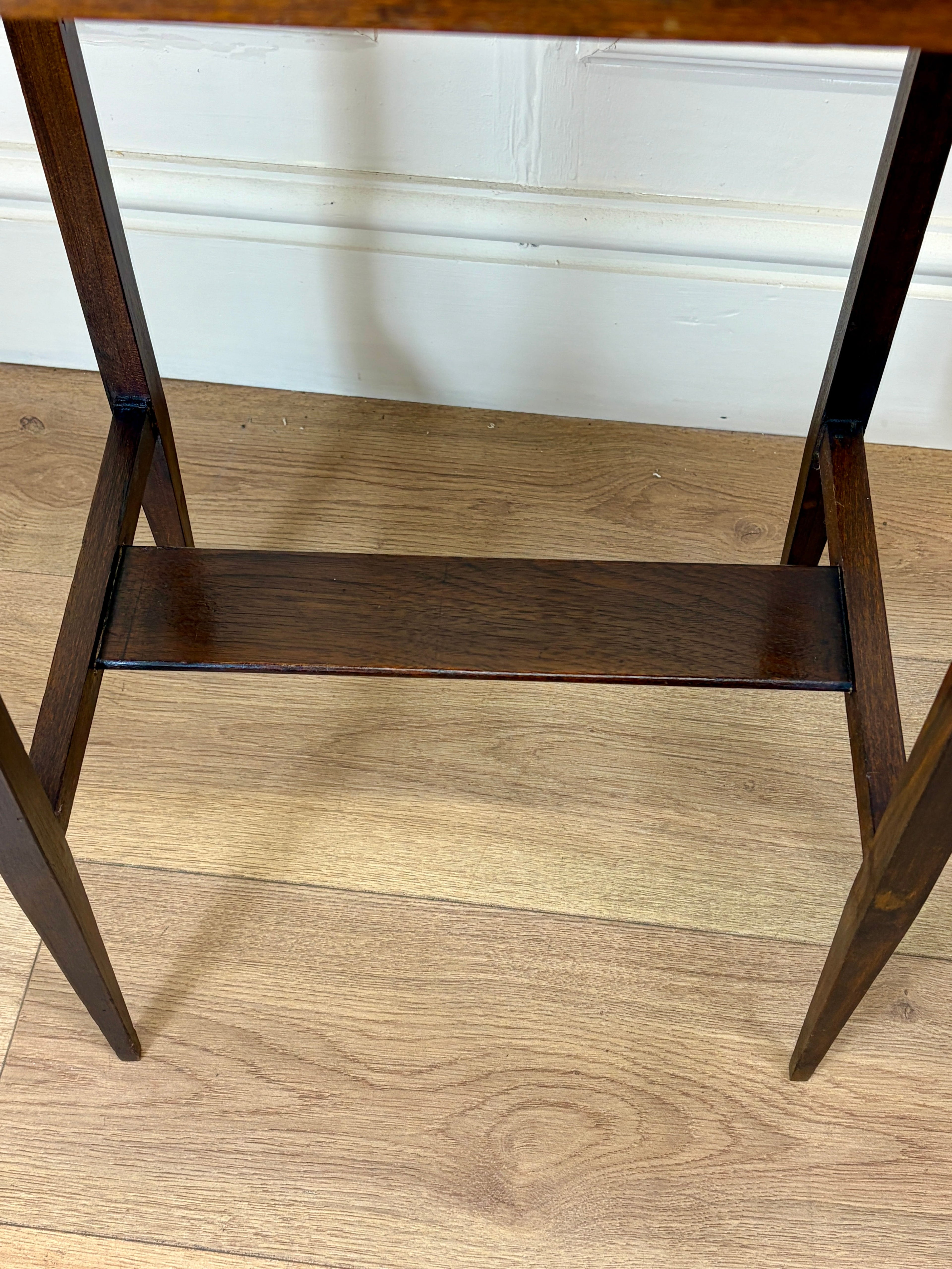 Wooden bedside with shelf with two shelves on a wooden floor.