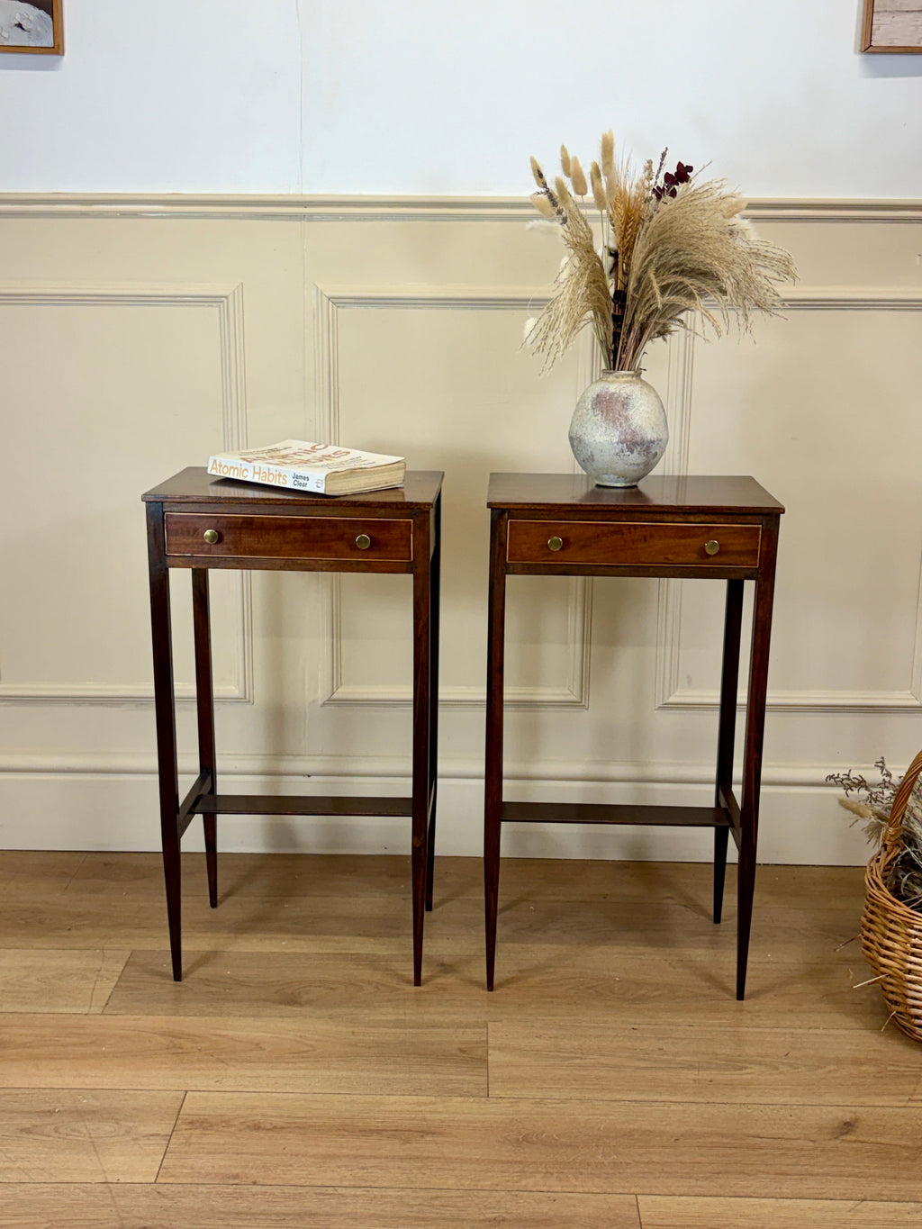 Two wooden side tables with a vase of dried plants on a light wood floor.