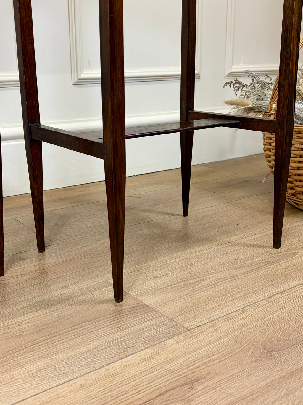 Wooden chair legs on a wooden floor with a white wall in the background
