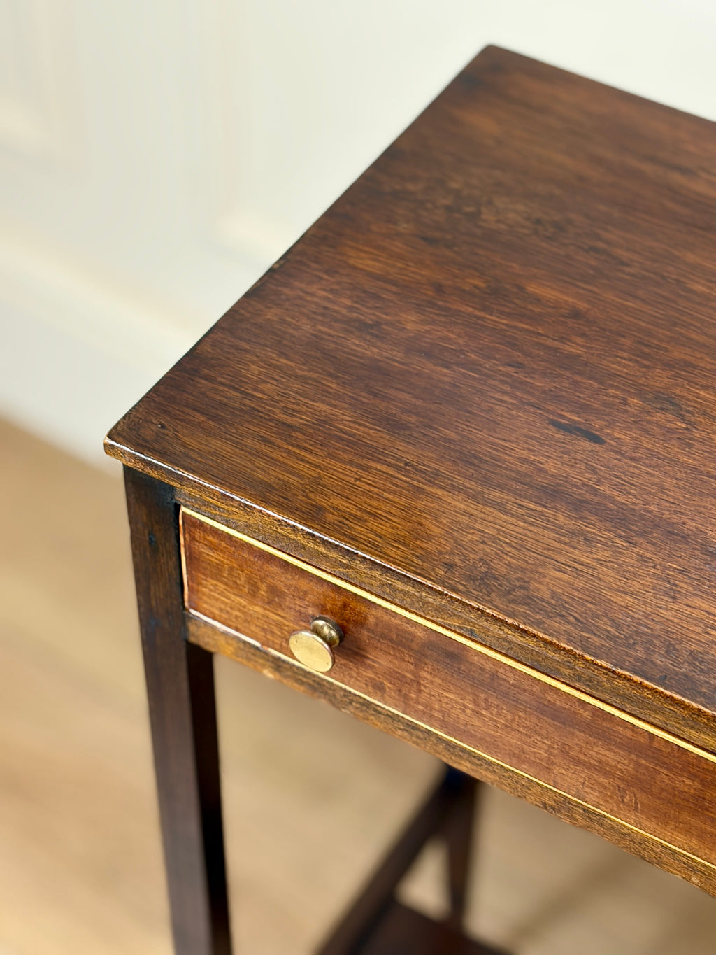 Wooden side table with a drawer and brass handle on a neutral background