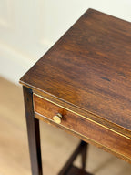 Wooden side table with a drawer and brass handle on a neutral background
