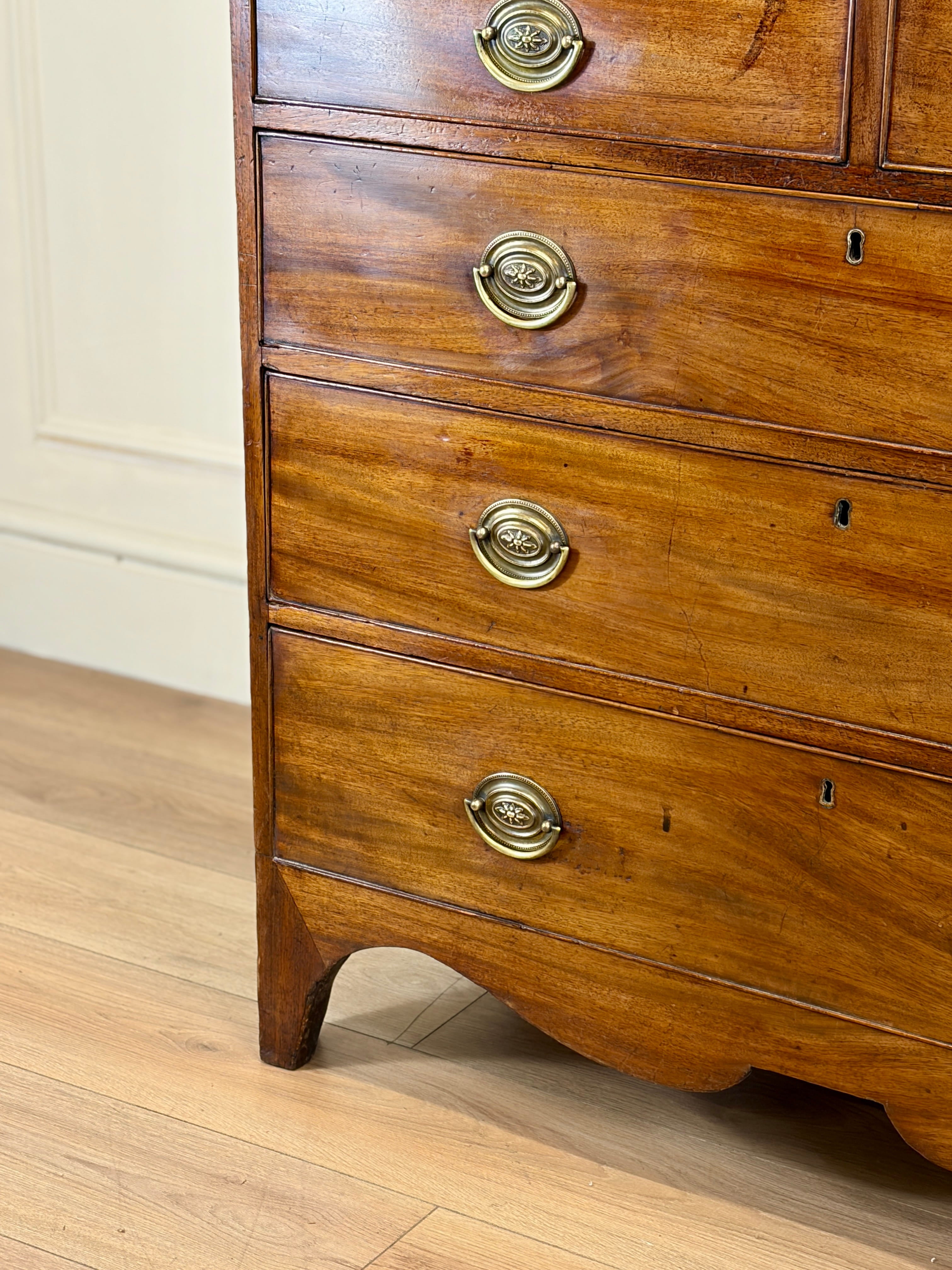 Wooden dresser with brass handles on a wooden floor.
