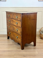 Wooden dresser with four drawers on a wooden floor.