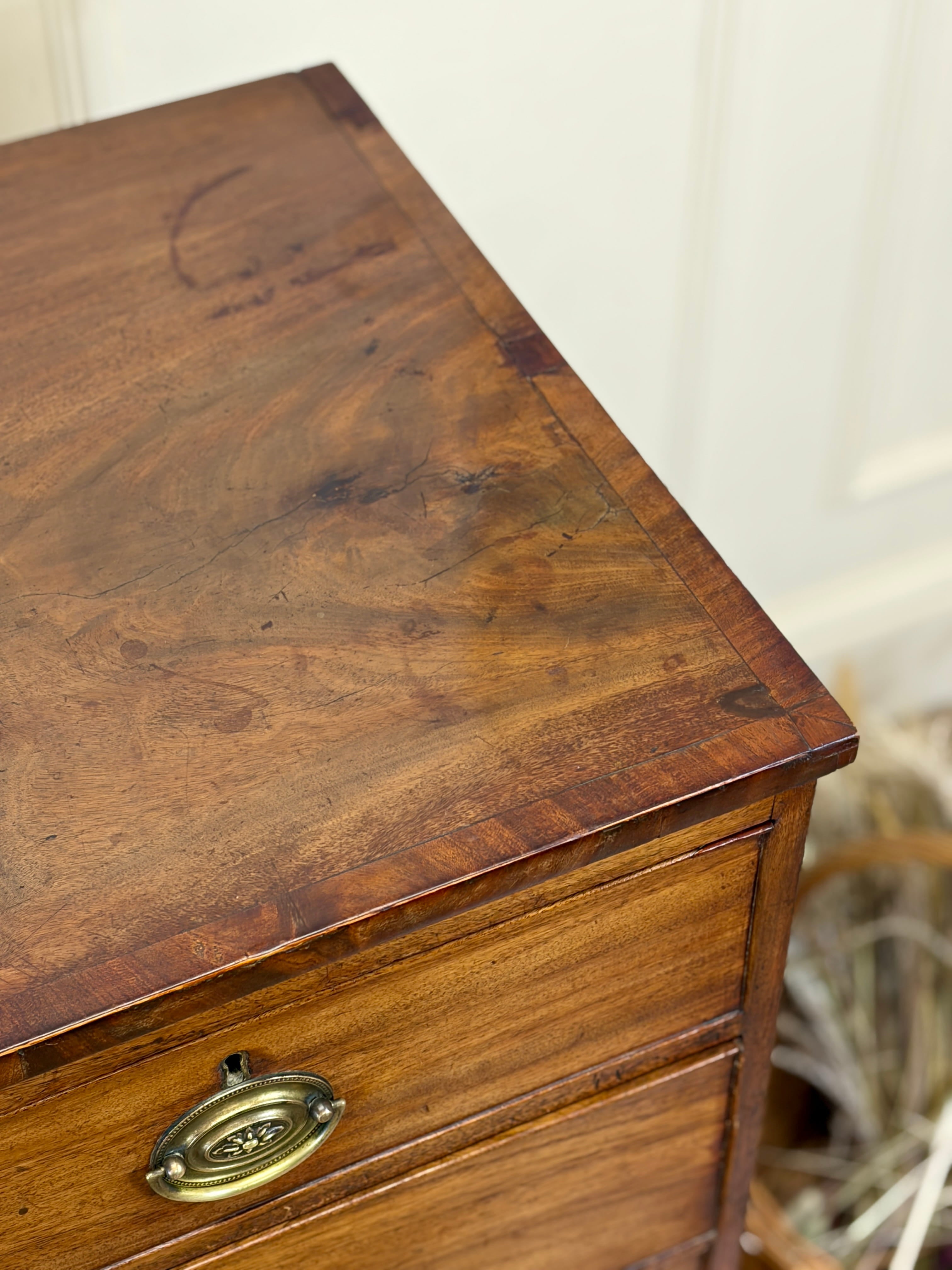 Close-up of a wooden dresser with a brass handle against a neutral background