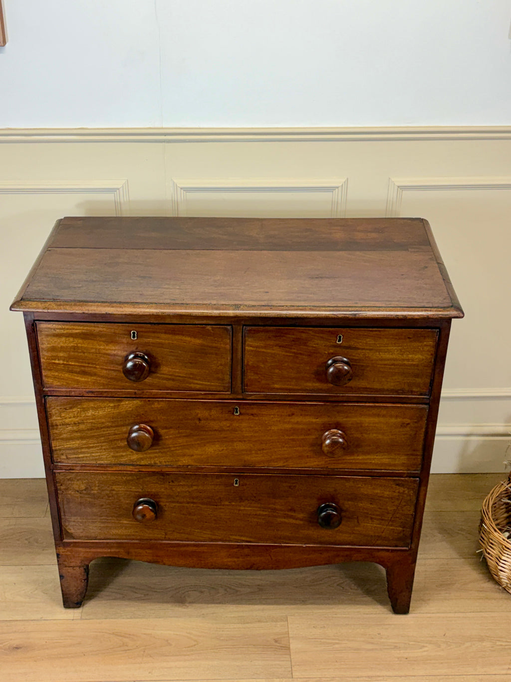 Wooden dresser with three drawers on a wooden floor against a white wall.