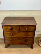 Wooden dresser with three drawers on a wooden floor against a white wall.