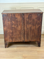 Vintage wooden cabinet with a weathered finish on a wooden floor.