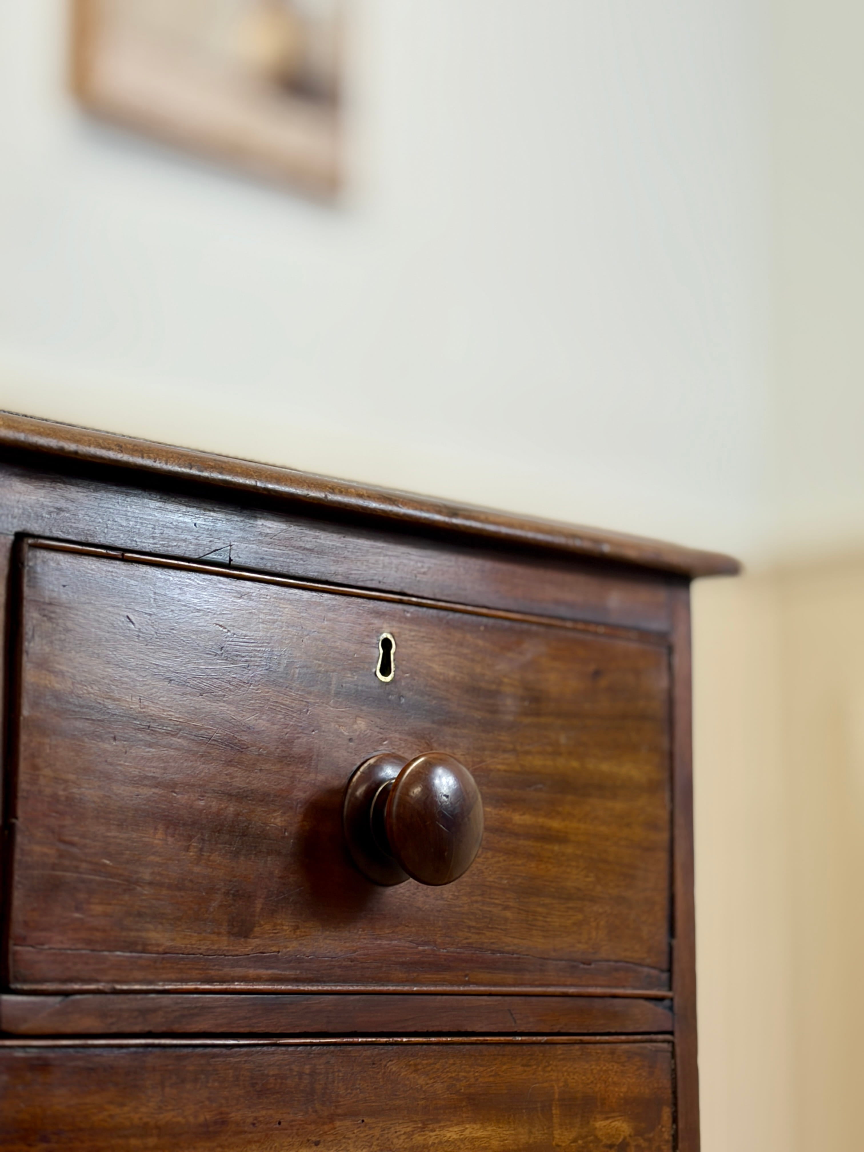 Close-up of a wooden drawer with a knob on a light-colored wall.