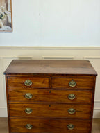 Wooden dresser with brass handles against a white wall