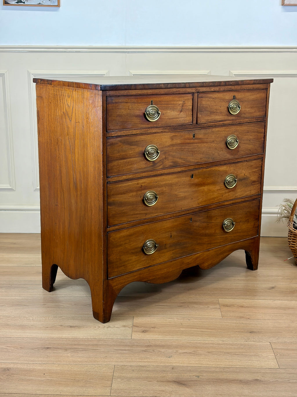 Wooden dresser with brass handles on a wooden floor.