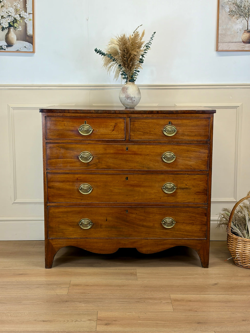 Wooden dresser with brass handles in a room with decorative elements.