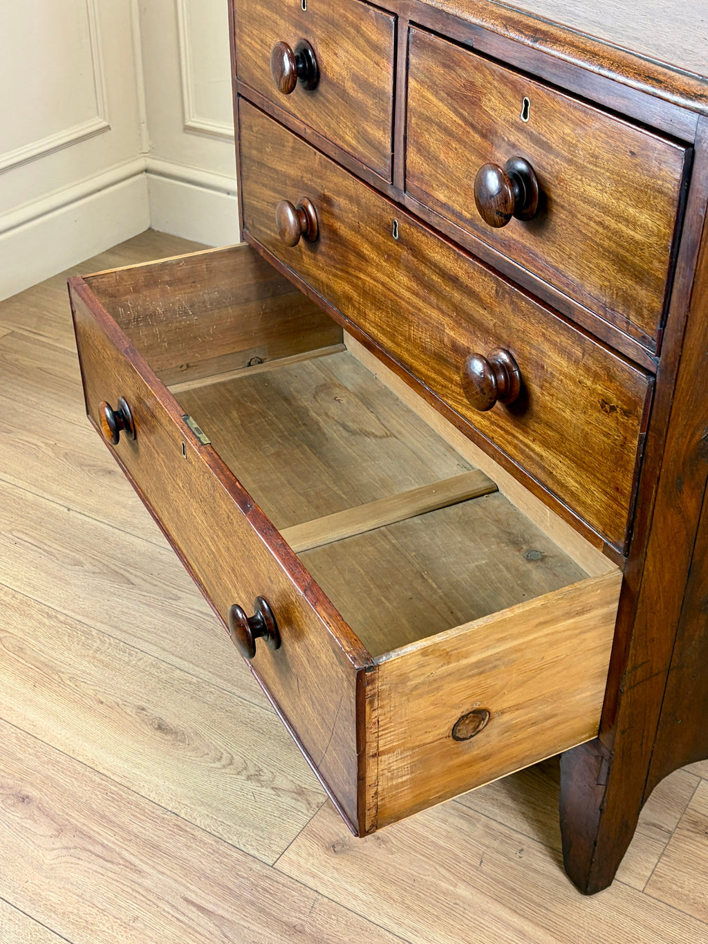 Wooden dresser with open drawer on a wooden floor