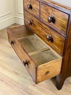 Wooden dresser with open drawer on a wooden floor