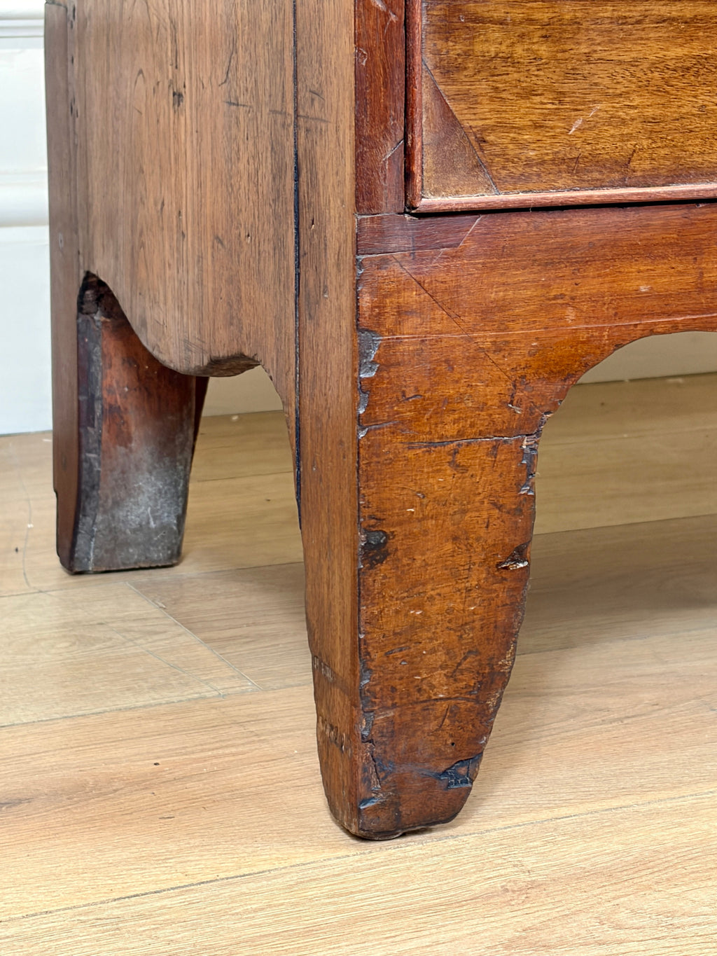 Close-up of a wooden drawer with visible wear on a wooden floor.