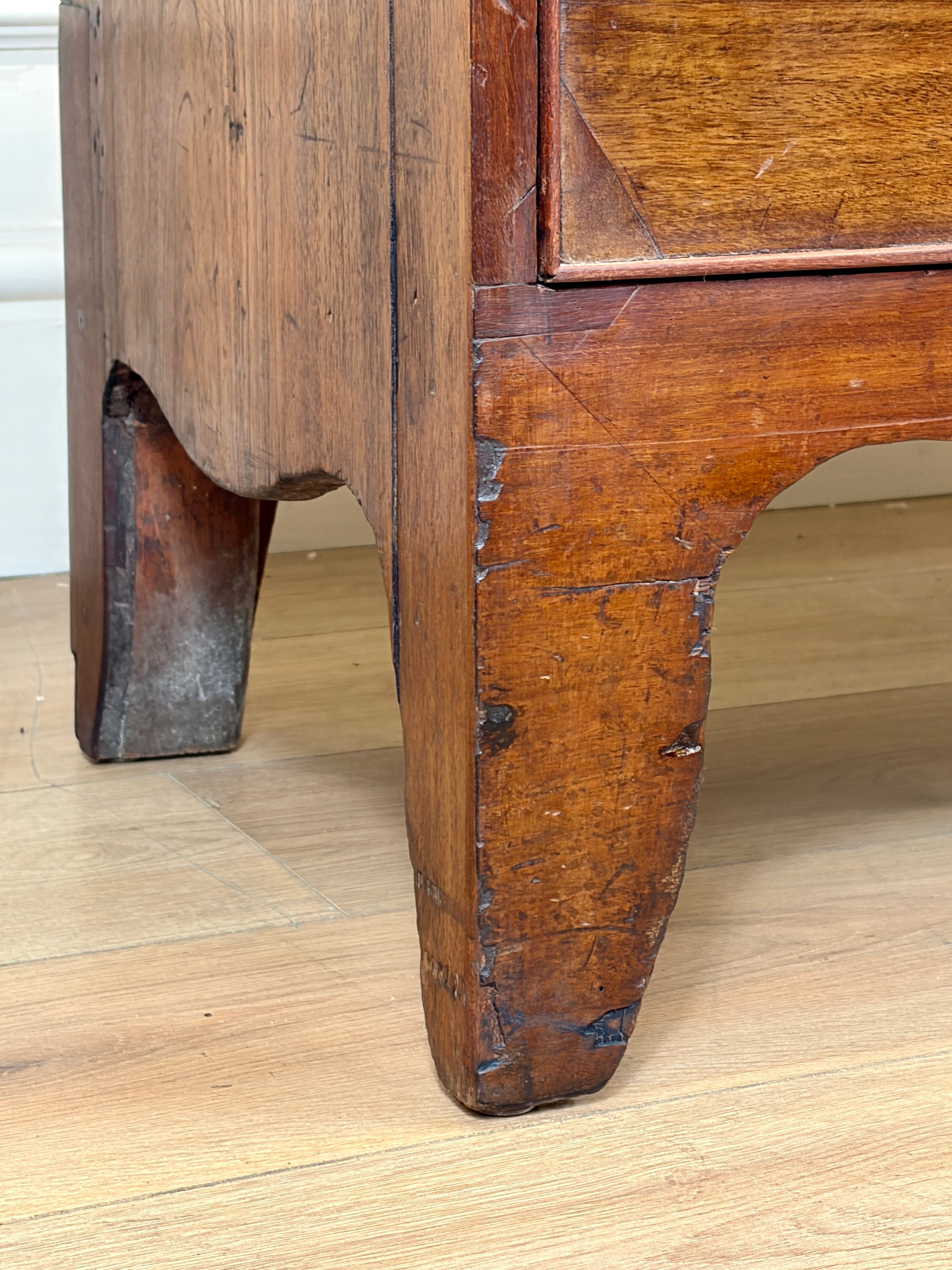 Close-up of a wooden drawer with visible wear on a wooden floor.