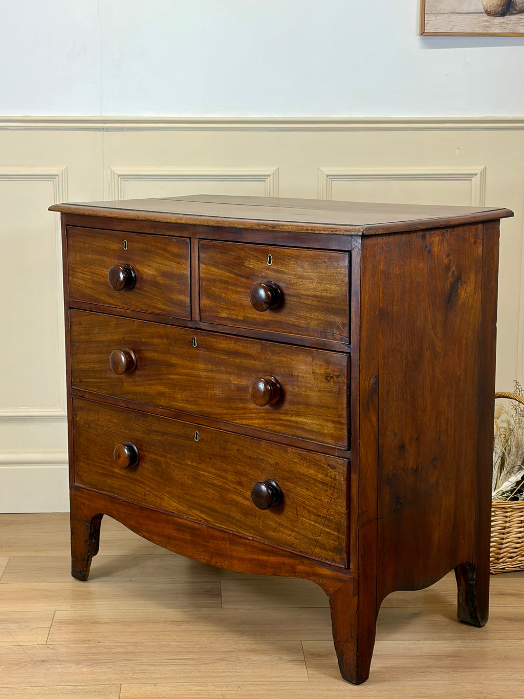 Wooden dresser with four drawers on a wooden floor against a light blue wall.