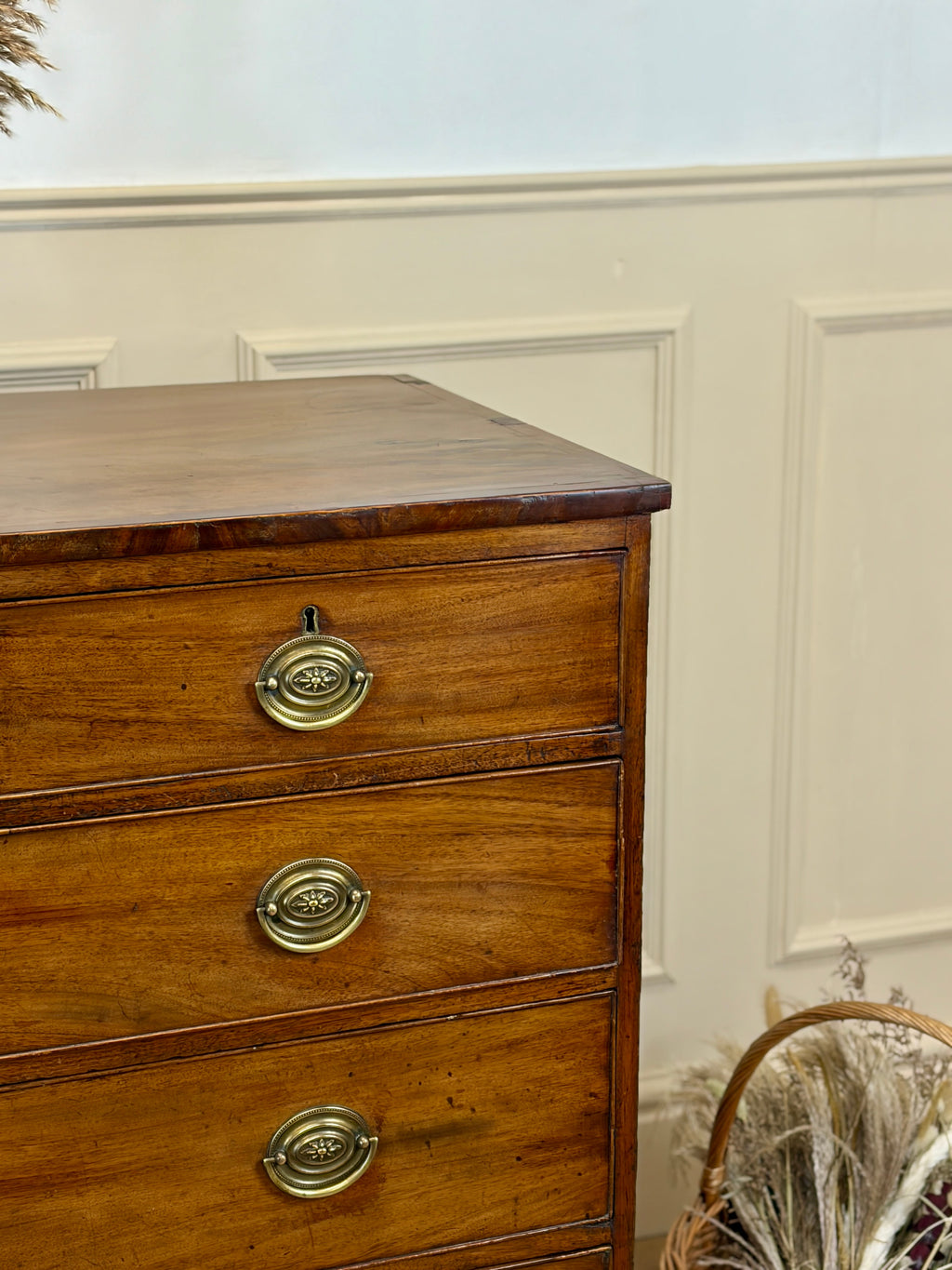 Wooden dresser with brass handles against a white wall
