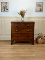 Wooden dresser with decorative items in a room with wainscoting and framed pictures.