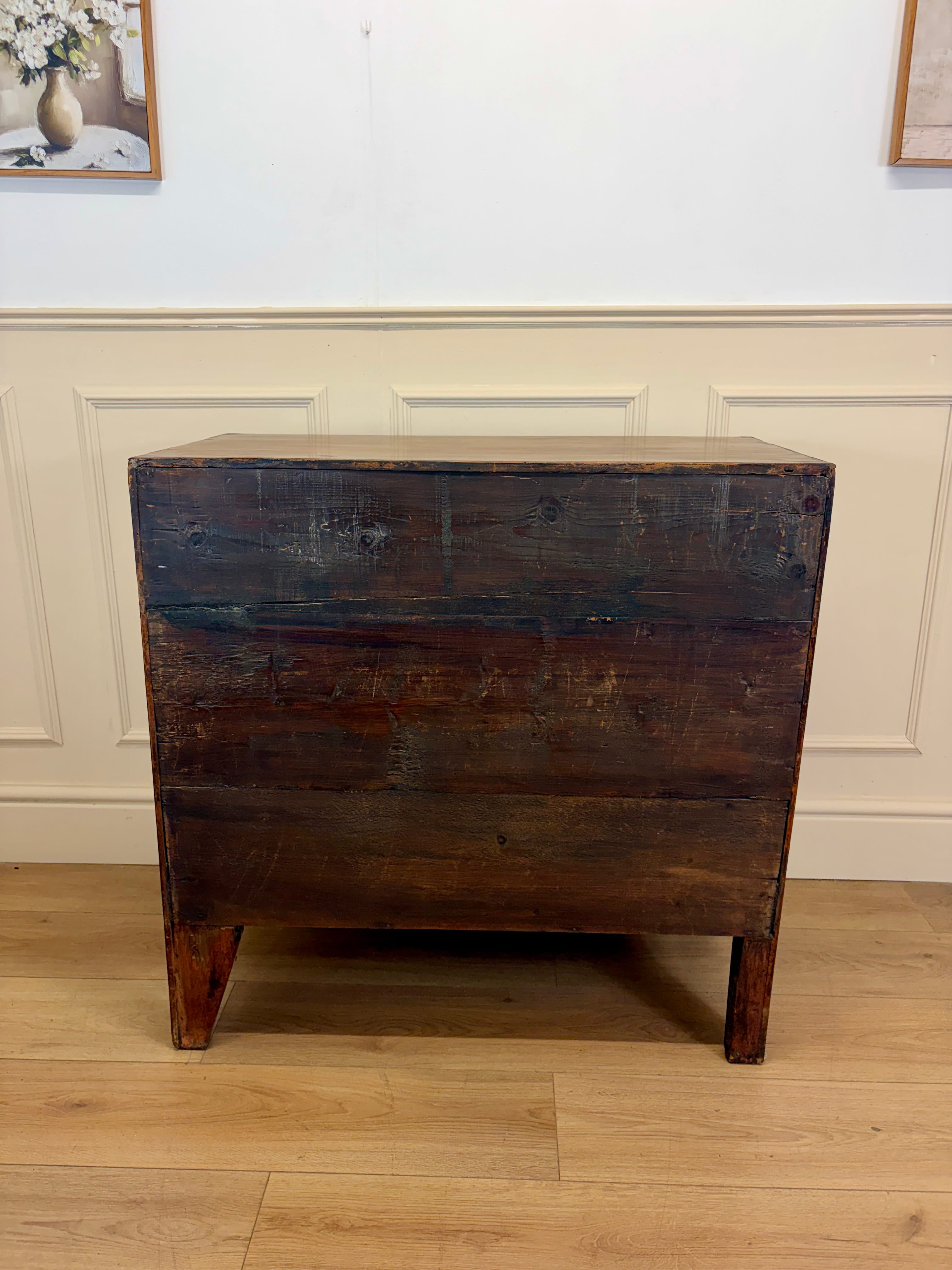 Wooden dresser with a distressed finish in a room with white walls and wooden flooring.