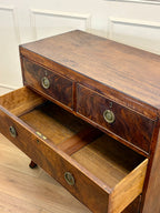 Wooden sideboard with open drawer against a white paneled wall.