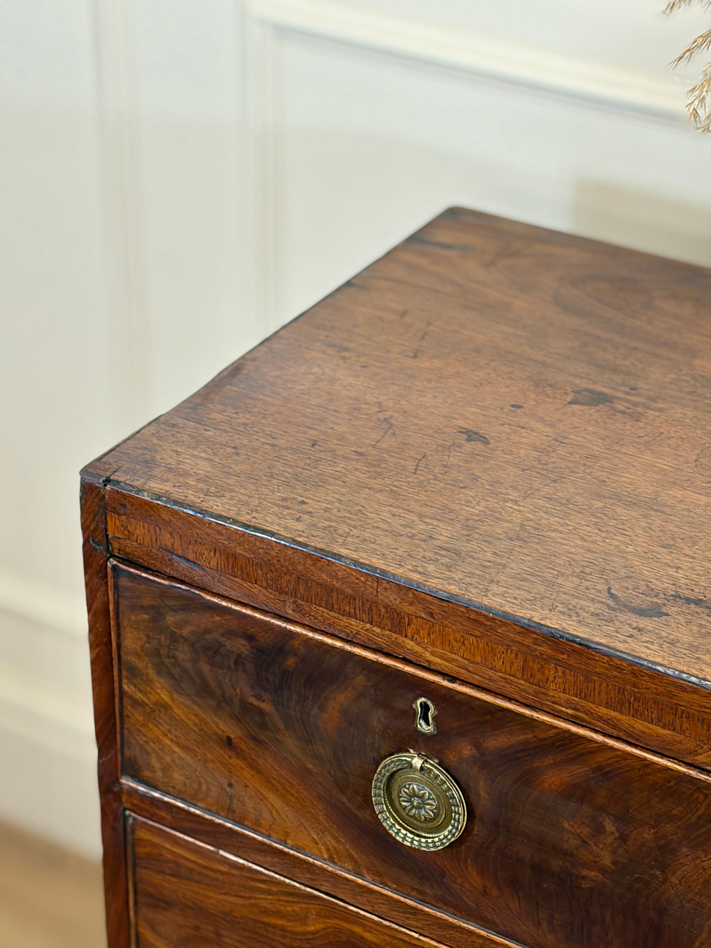 Wooden drawer with a decorative metal plaque on a neutral background