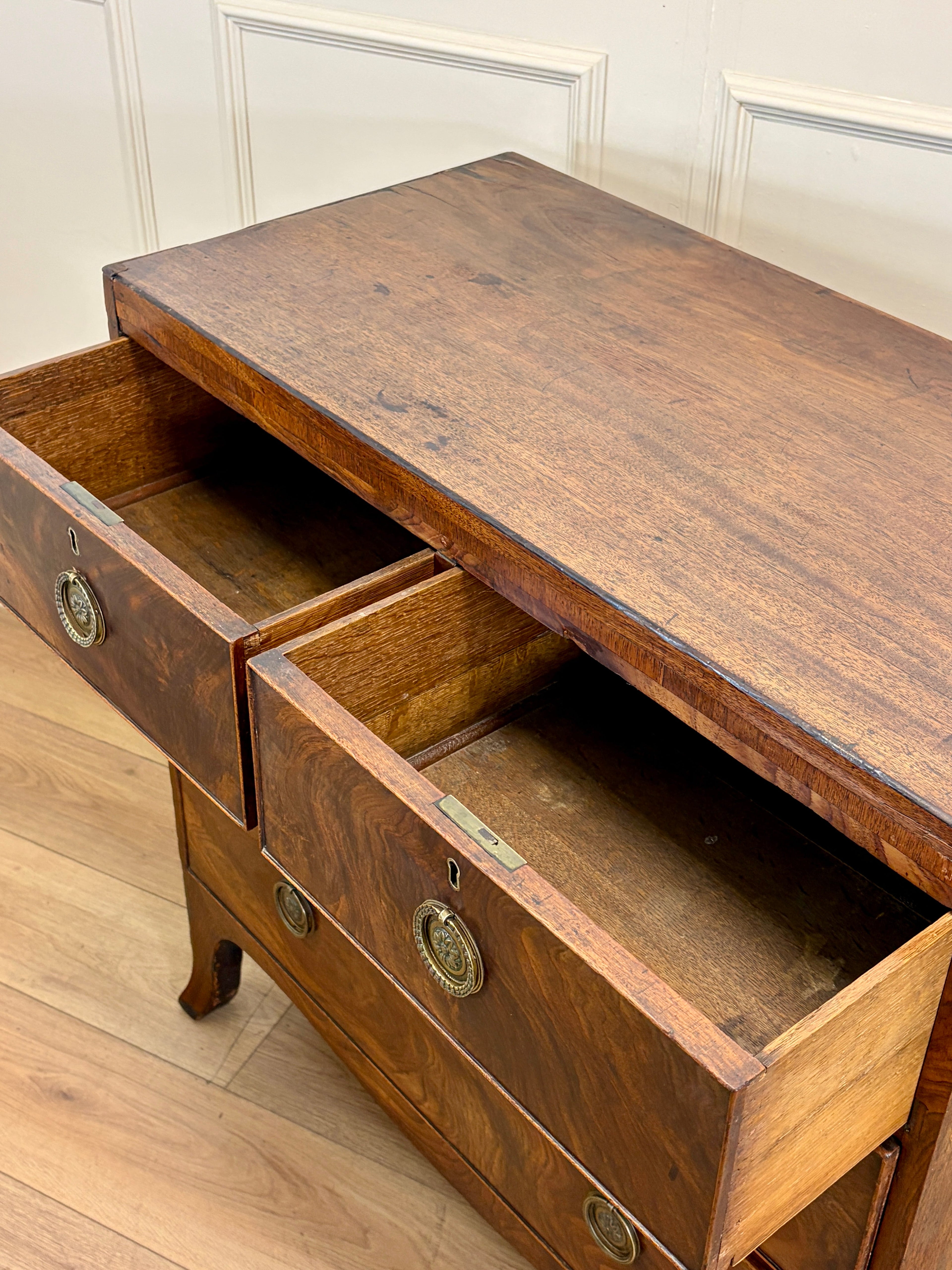Wooden dresser with open drawers on a wooden floor.
