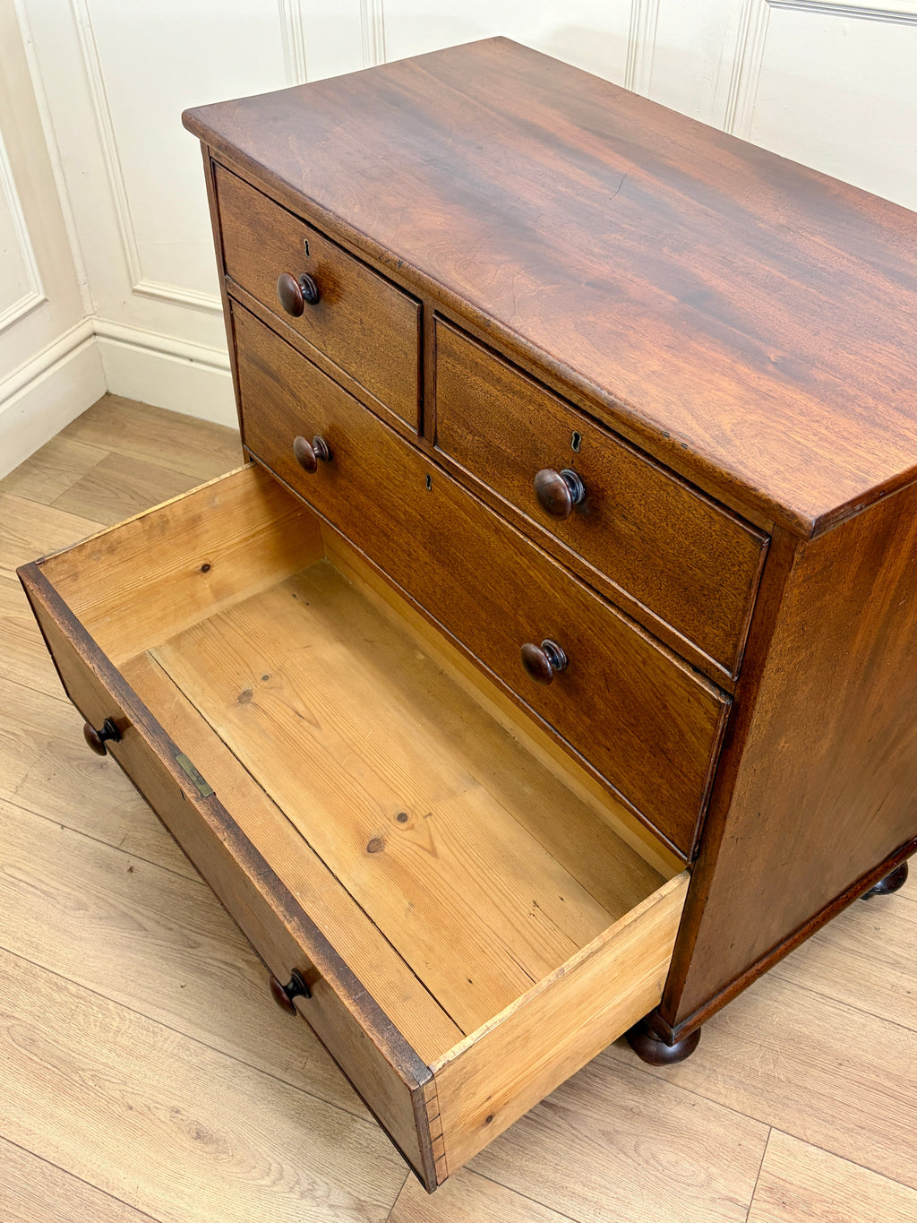 Wooden dresser with open drawer on a wooden floor