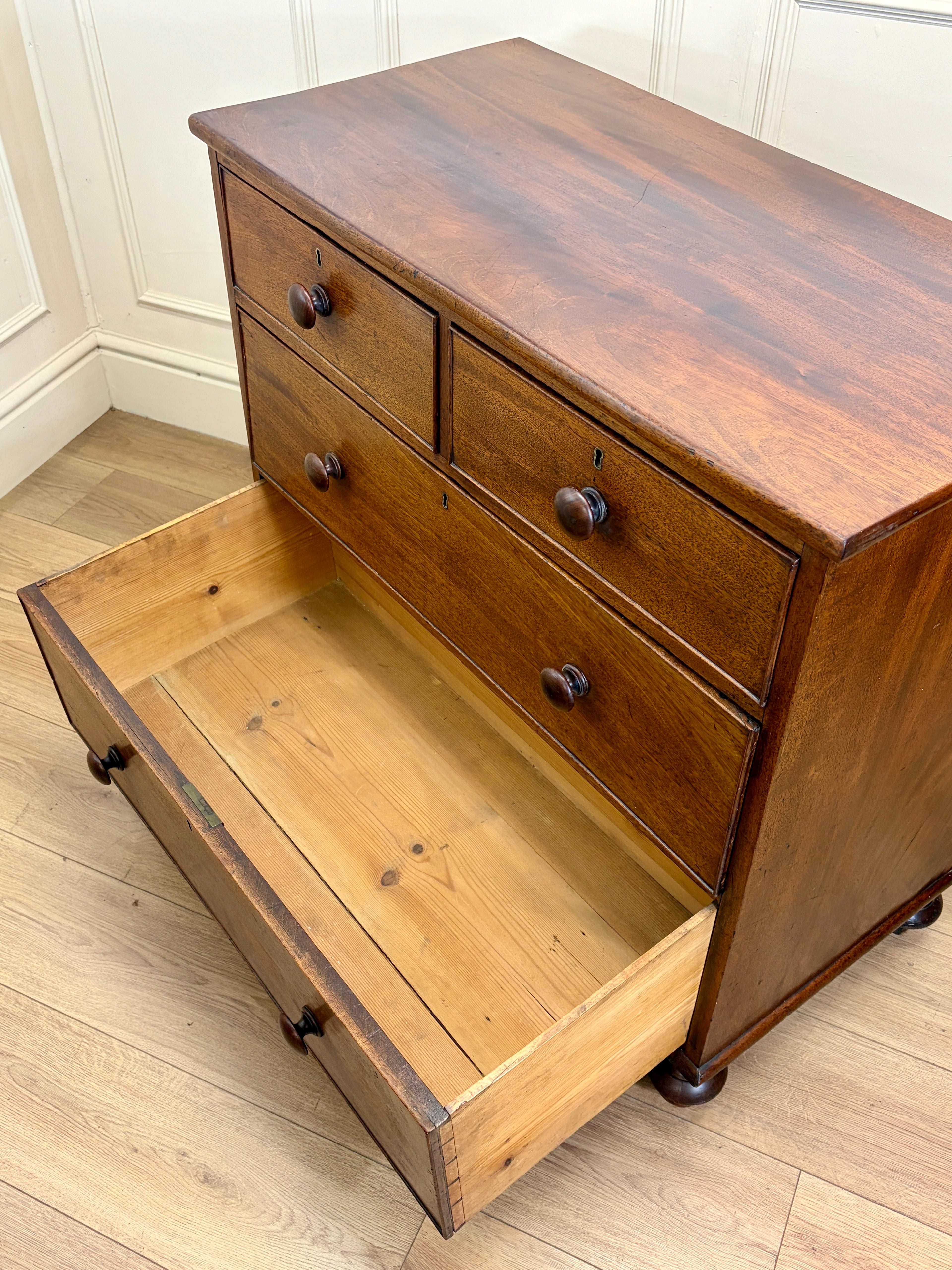 Wooden dresser with open drawer on a wooden floor