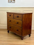 Wooden dresser with four drawers on a wooden floor.