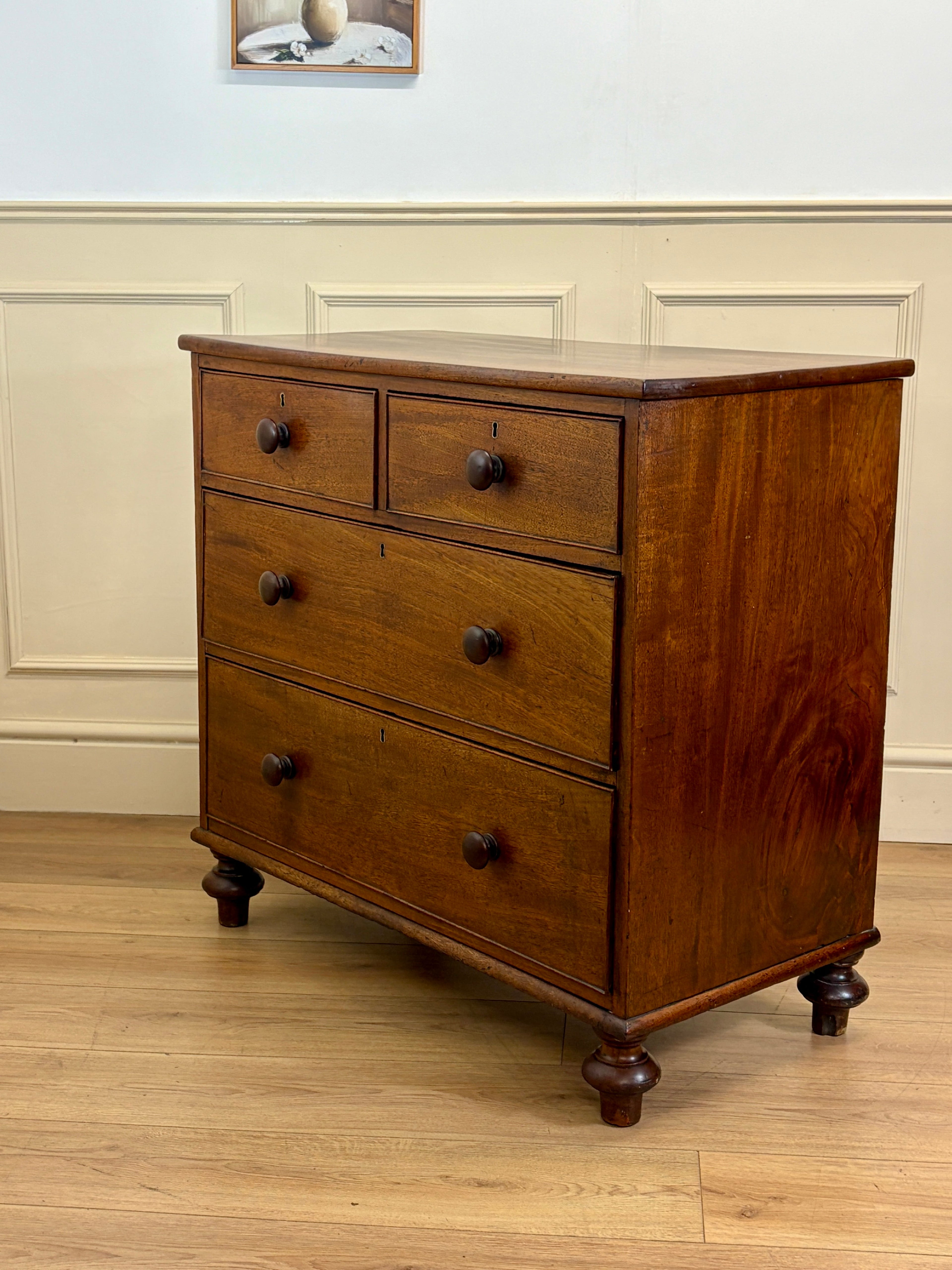 Wooden dresser with four drawers on a wooden floor.