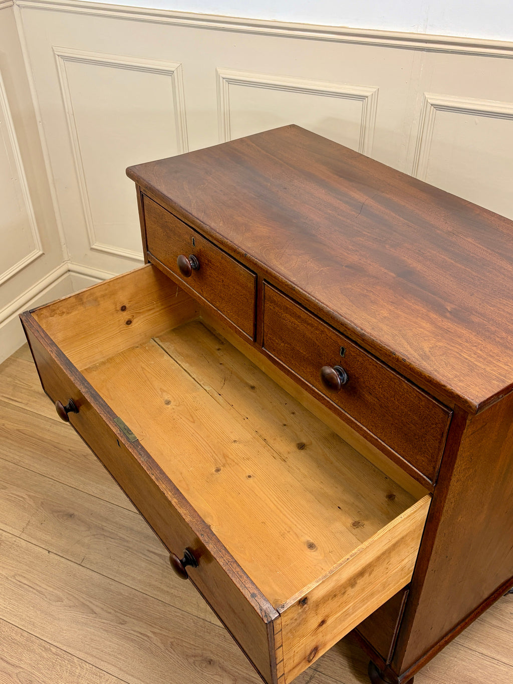 Wooden bench with drawers against a white paneled wall.