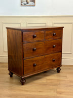 Wooden dresser with three drawers on a wooden floor against a white wall.