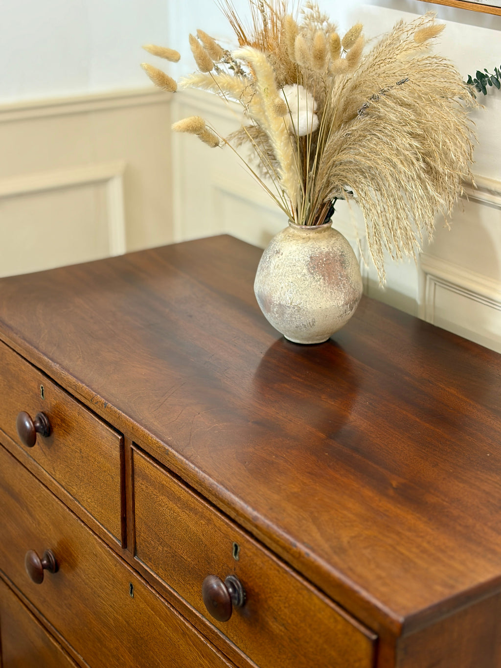 Decorative vase with dried plants on a wooden dresser