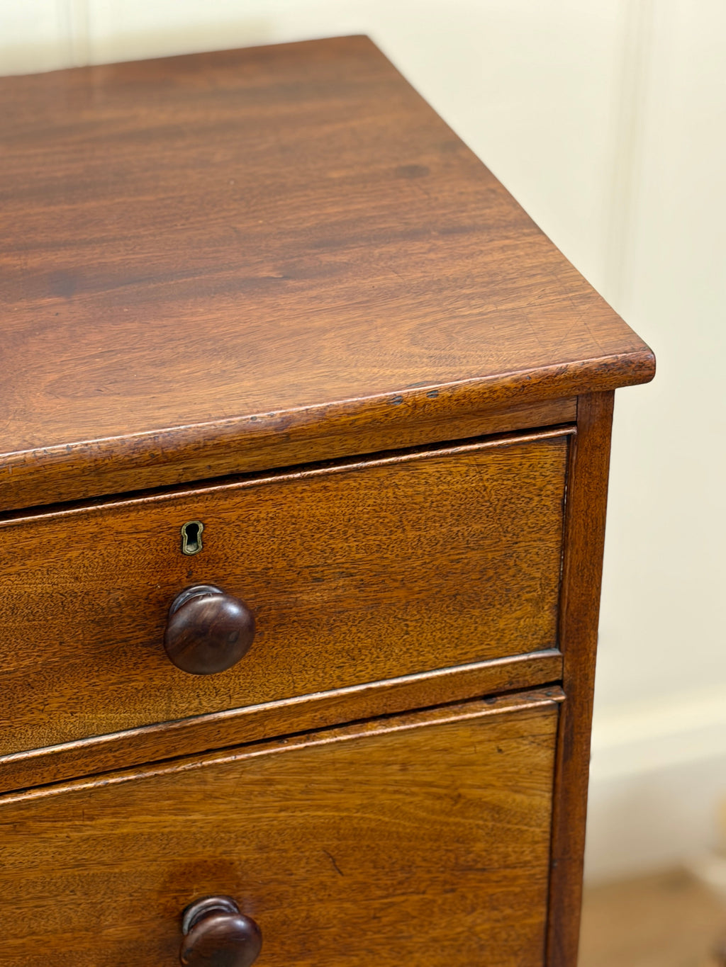 Wooden drawer with two knobs on a wooden surface.